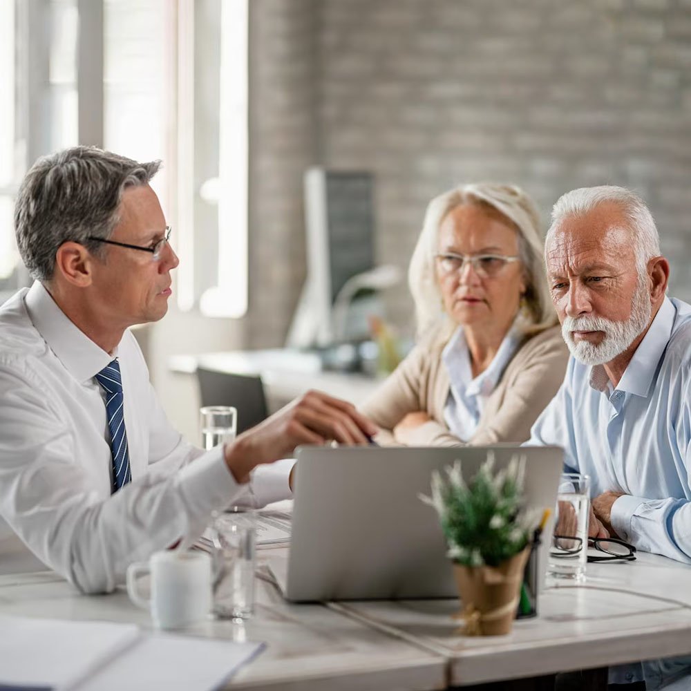 Mature couple and their bank manager using computer while having consultations in the office